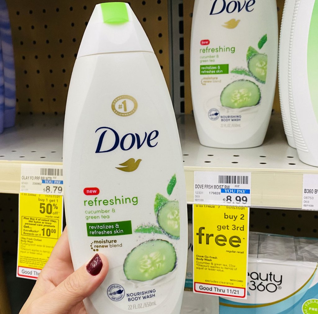 woman with dark red nails holding up a bottle of dove cucumber body wash next to yellow sale tag at cvs