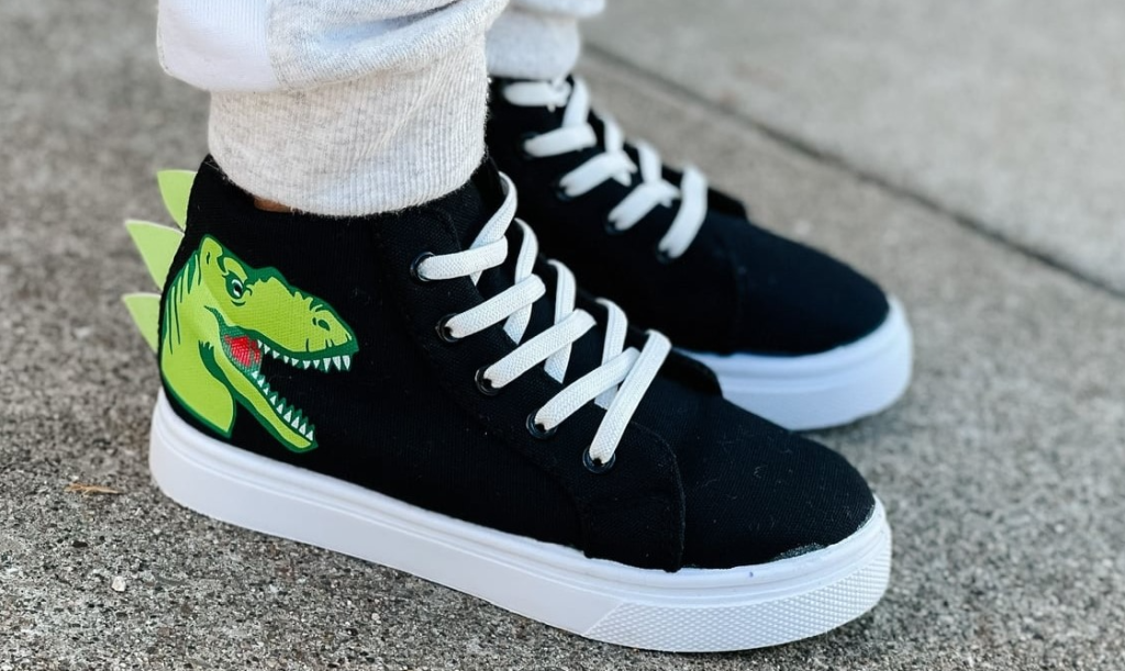 kid wearing sneakers with a dinosaur on them