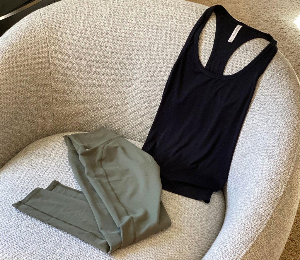 black workout tank and olive green leggings laying on grey accent chair