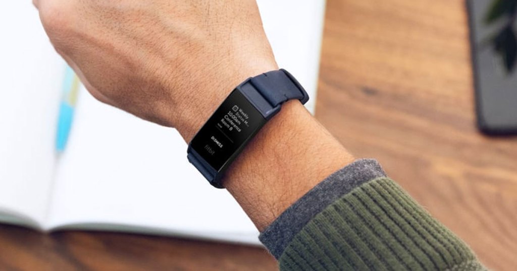 man wearing a green sweater with a black fitbit charge on his wrist