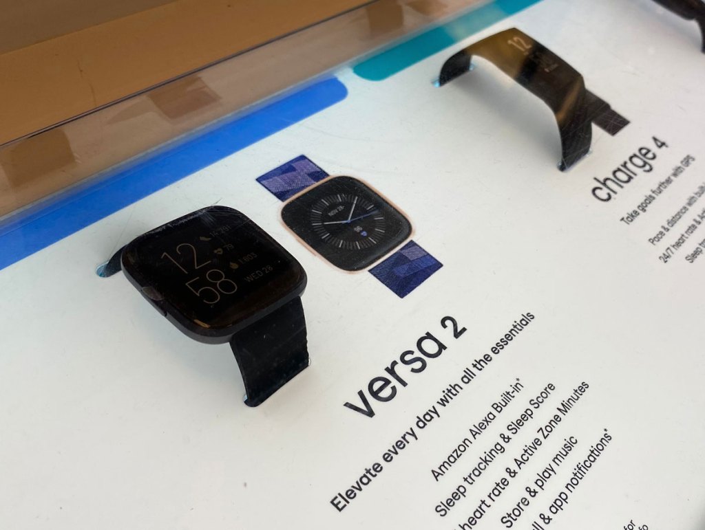 display of black fitbit versa and fitbit charge 4 fitness trackers