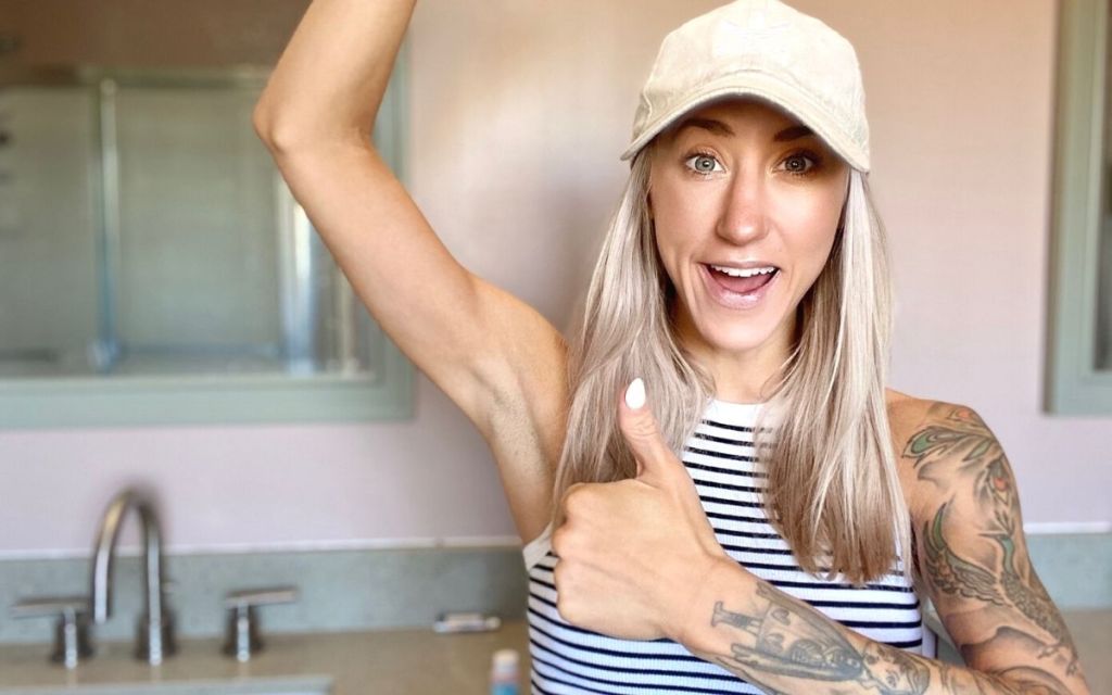A woman holding up arm and making a thumbs up gesture in a bathroom