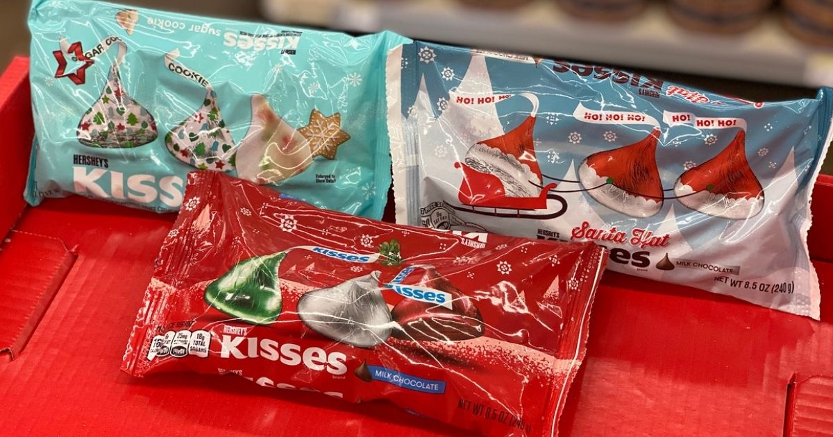 Three bags of holiday-themed Hershey's kisses on a red surface