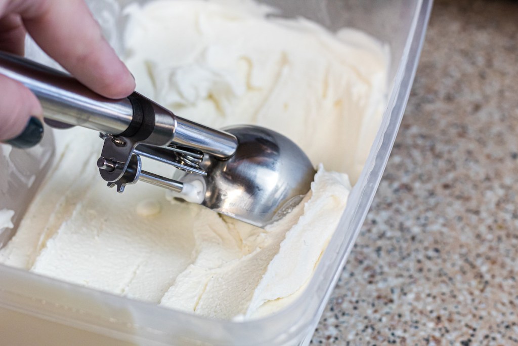 hand scooping out vanilla ice cream