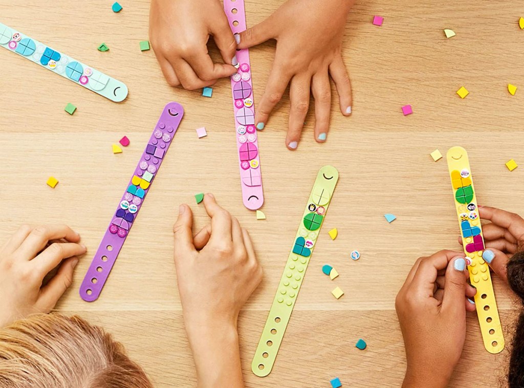 kids decorating lego dots bracelets on a wood table