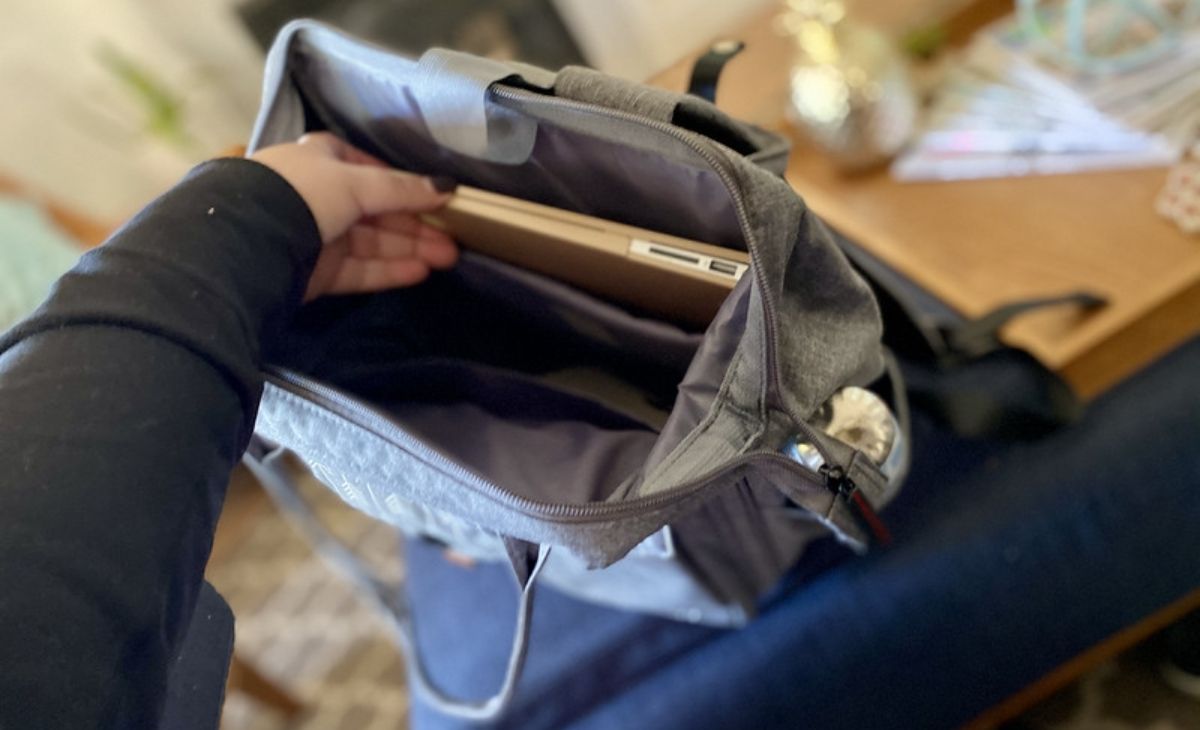 A hand placing a laptop in a bag