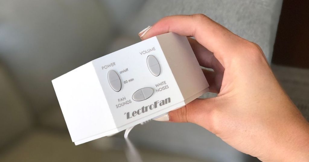 A hand holding a white noise sound machine