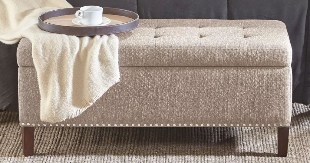 storage ottoman with a blanket and tray on it