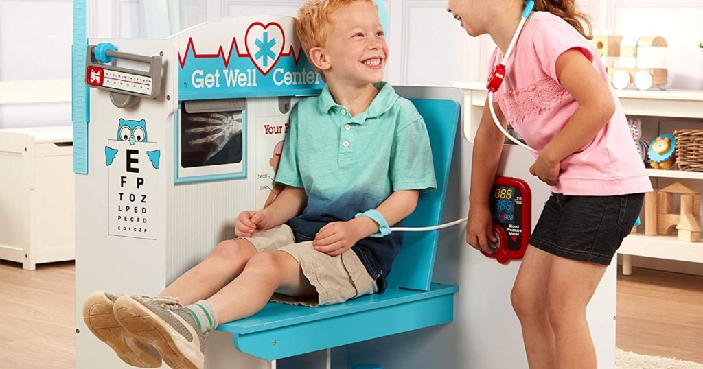 boy and girl playing with a large wood doctor office playset