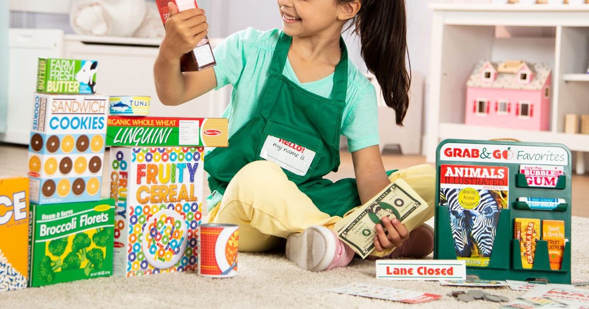 girl on floor playing with grocery store toys