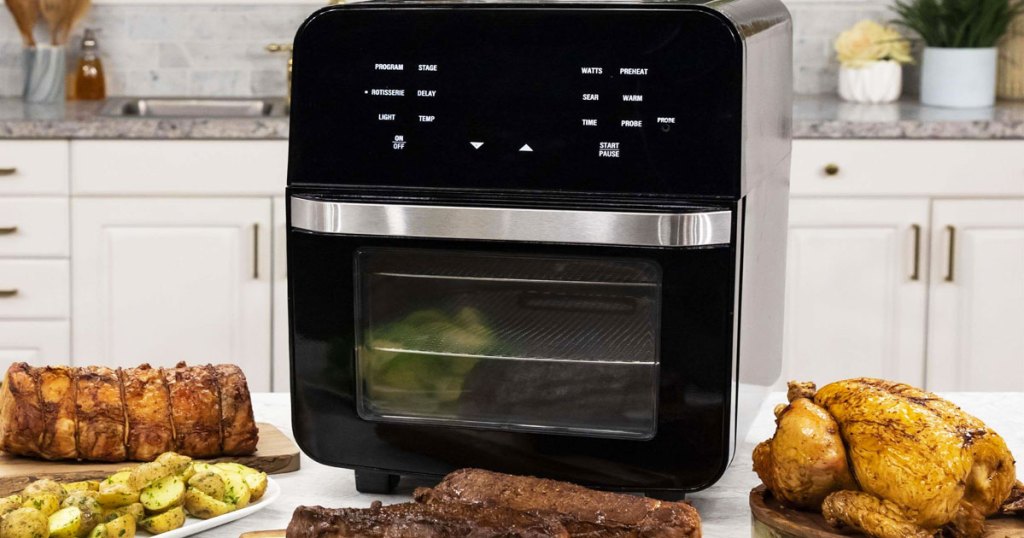 large black square nuwave air fryer oven on kitchen counter with plates of food surrounding it