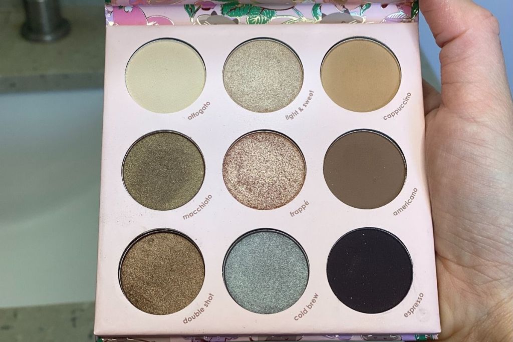A hand holding an eyeshadow palette