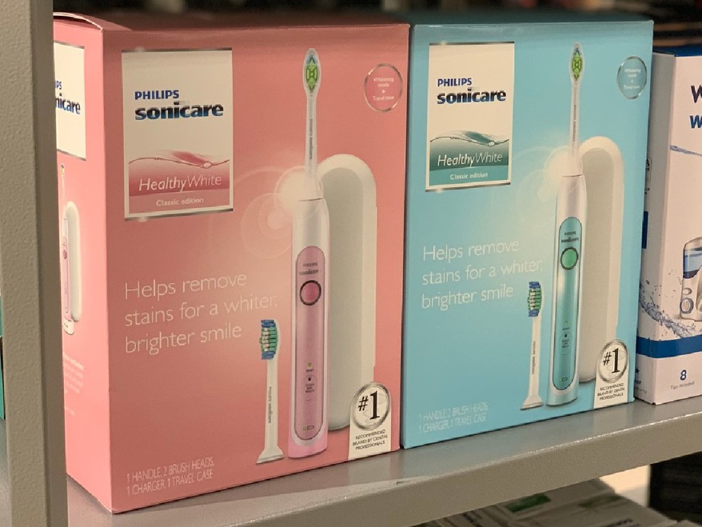 one blue electric toothbrush box and one pink electric toothbrush box on store shelf