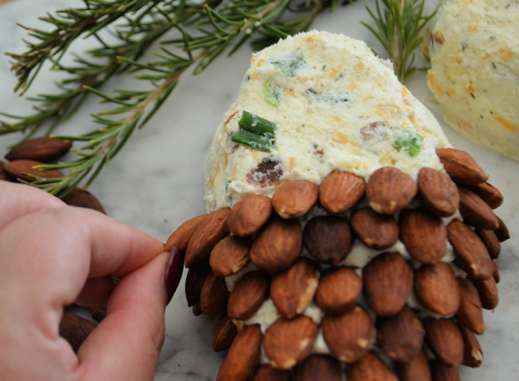 Placing almonds onto a pine cone cheese ball