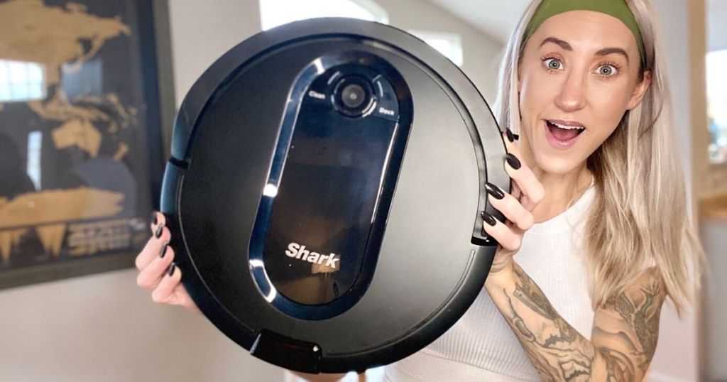 A woman holding a smart vacuum and smiling