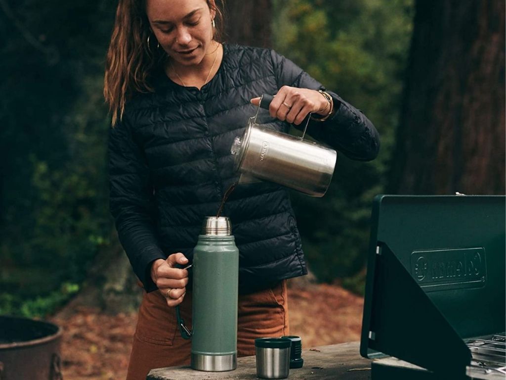 woman pouring coffee into green thermos