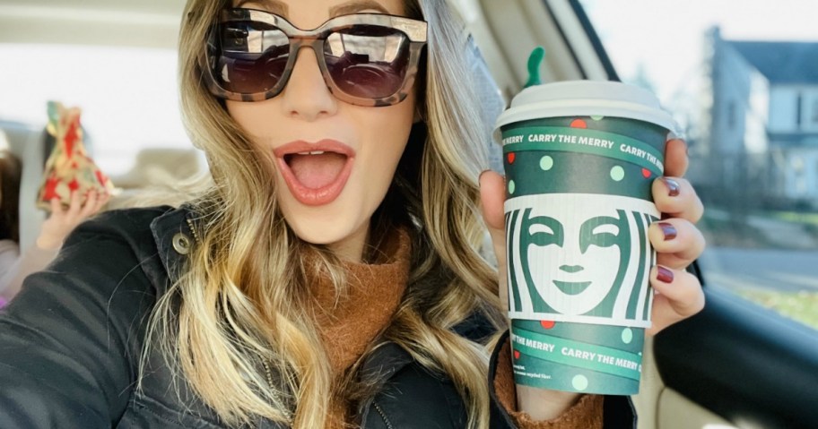 Woman holding Starbucks holiday cup and looking excited