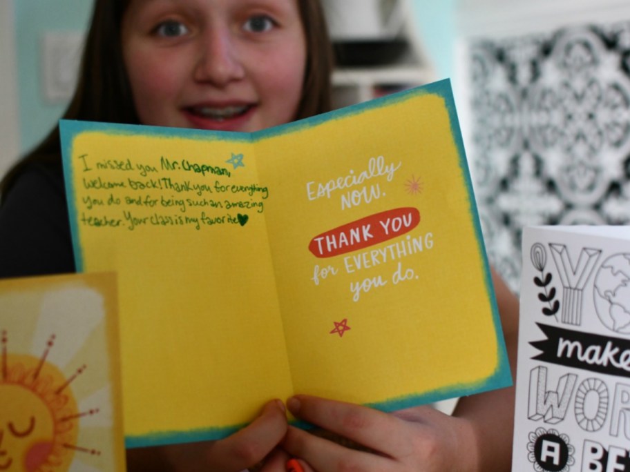 Girl holding up teacher thank you card with her note