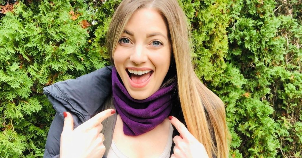woman with excitement on her face pointing at her neck gaiter