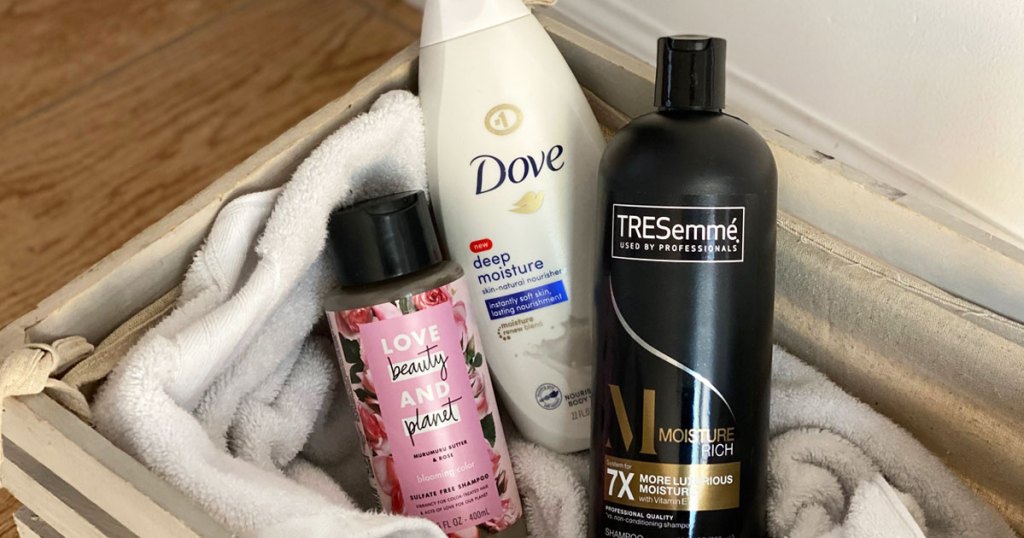 dove body wash, tresemme, and love beauty and planet shampoo bottles inside a basket with bath towel