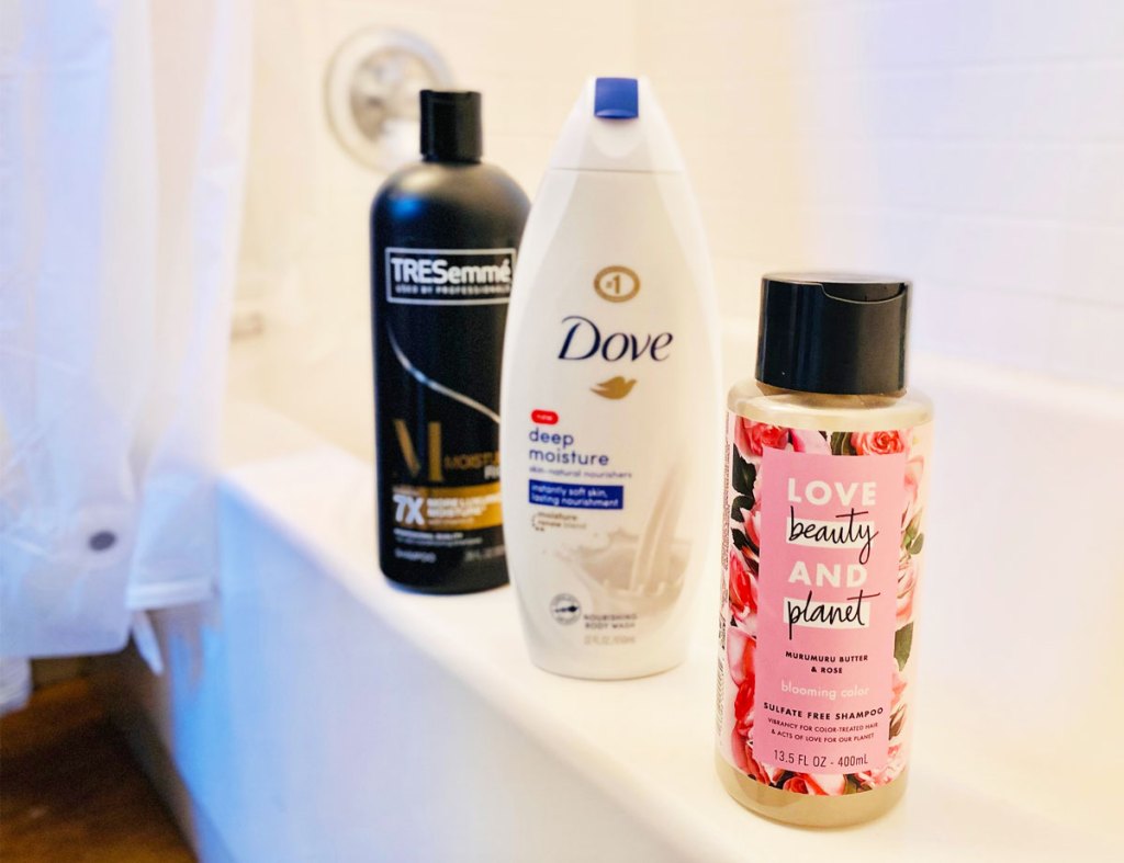 bottles of dove body wash, tresemme, and love beauty and planet shampoo sitting on edge of a bathtub