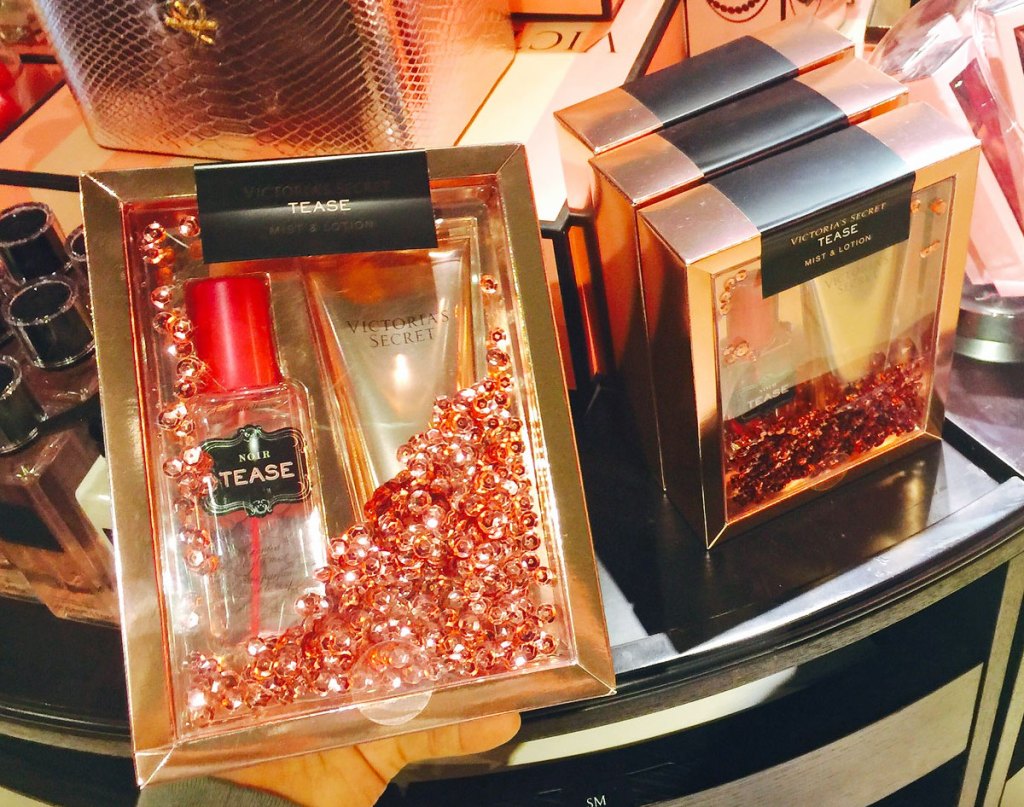 person holding up red and gold victoria's secret fragrance set