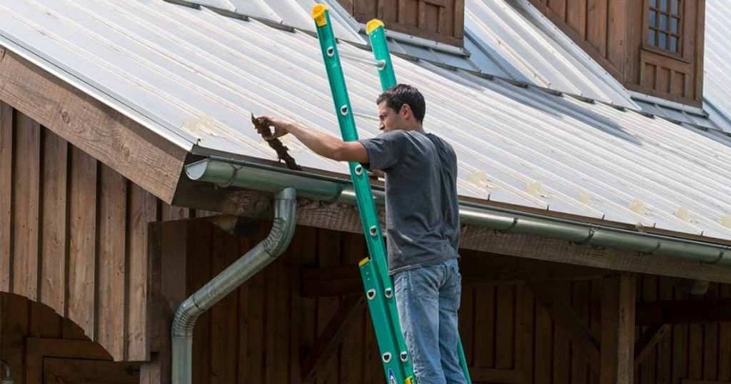 Man on a Werner Extension Ladder against a house with a metal roof