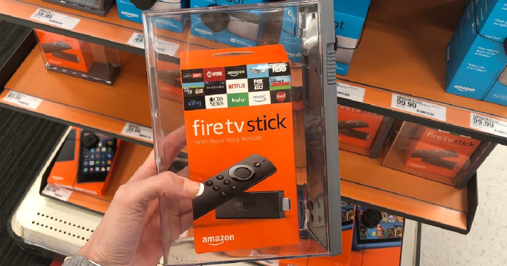 manicured hand holding box with Fire TV Stick in it by store display