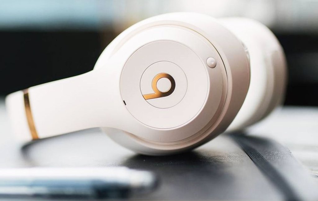 white pair of beats studio headphones with gold accents