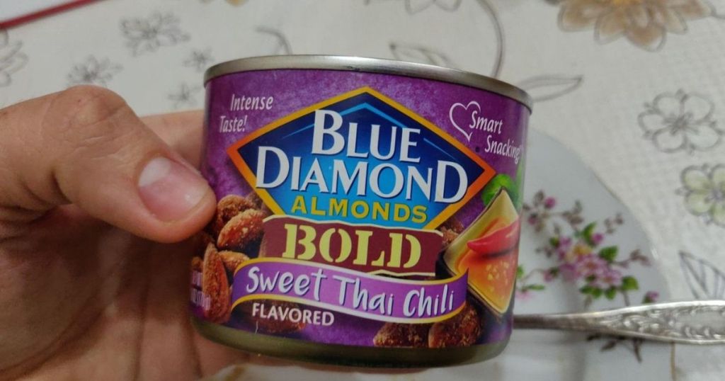 hand holding a can of blue diamond almonds in Sweet thai chili