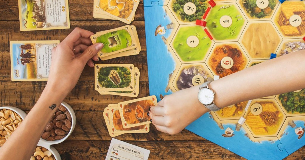 catan board game with hands playing