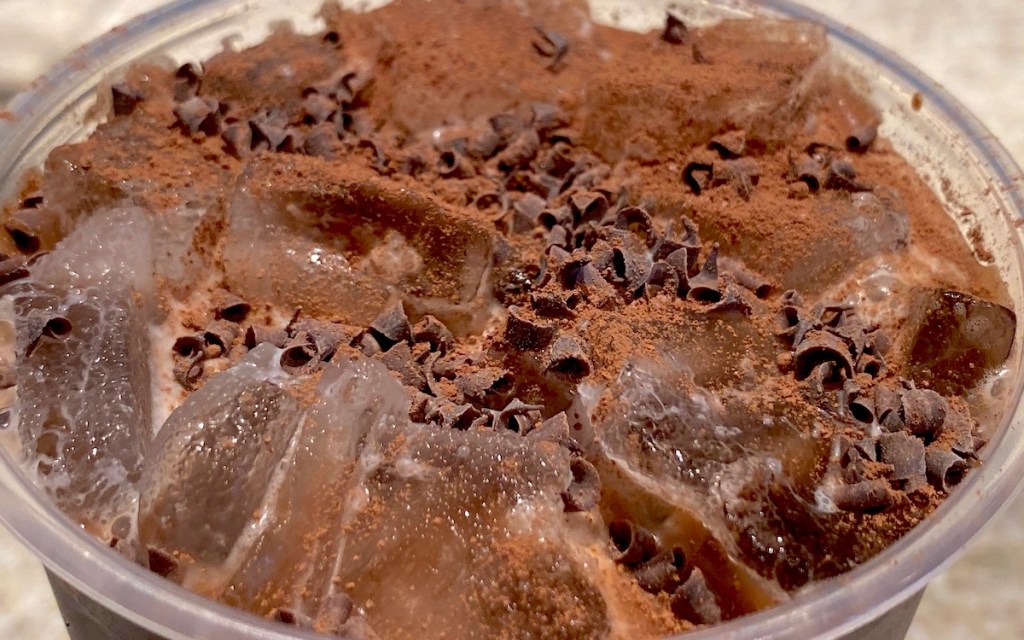 cup filled with ice and cocoa powder and chocolate curls