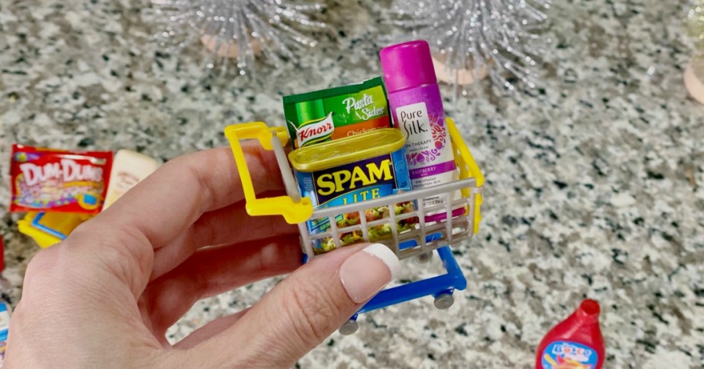 holding miniature shopping cart filled with 5 surprise mini brands