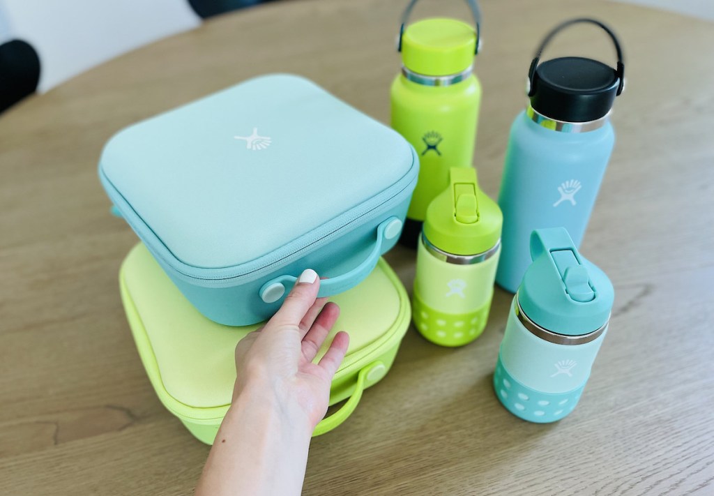 blue and green hydro flask lunchboxes and water bottles on wood table