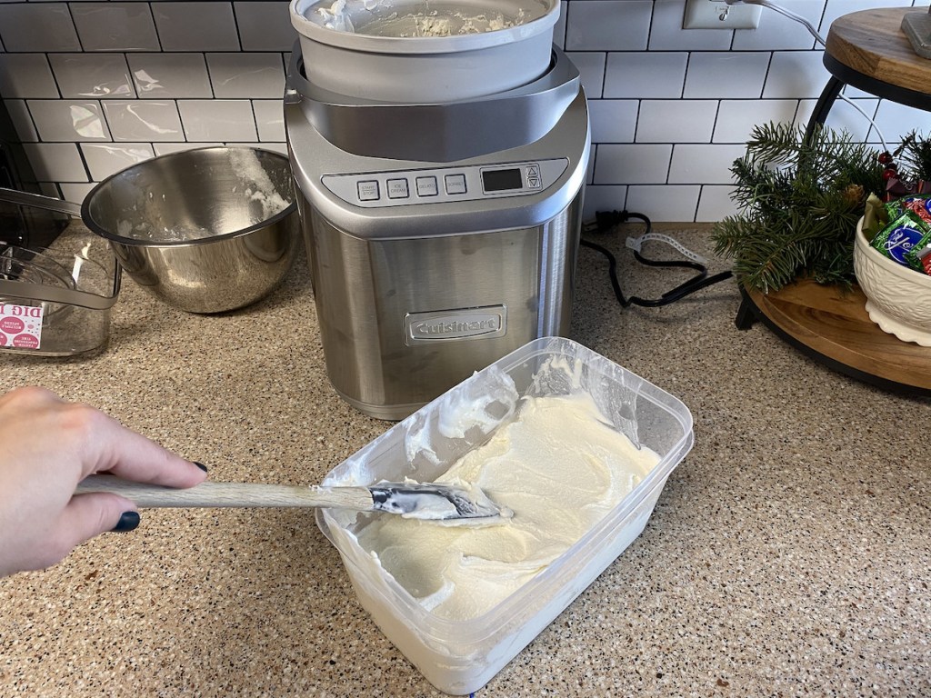 hand smoothing top of vanilla ice cream with rubber spatula