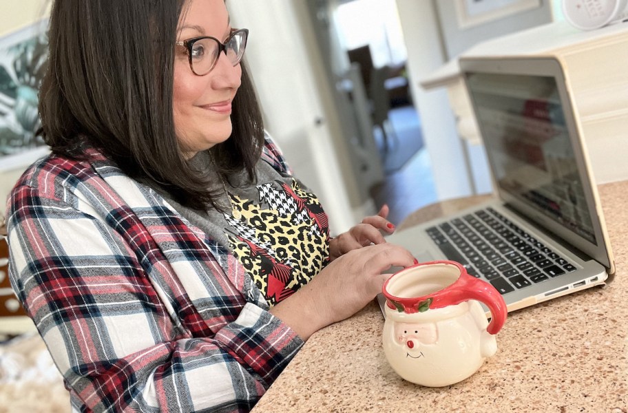 woman at counter looking at laptop with santa mug