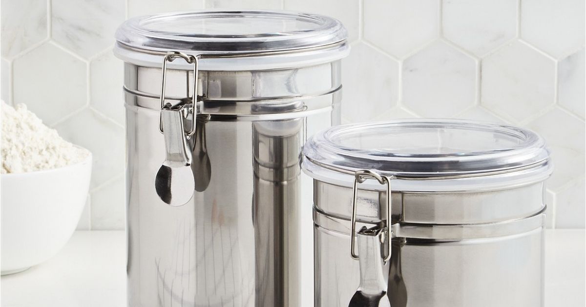 stainless steel canisters on counter top with white bowl of popcorn in background