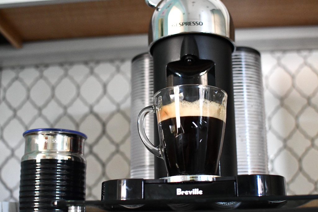 Nespresso Breville machine sitting on counter with black coffee in mug