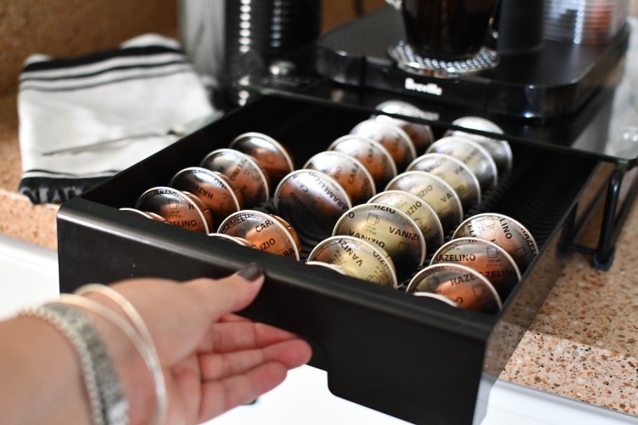 hand pulling drawer full of nespresso pods