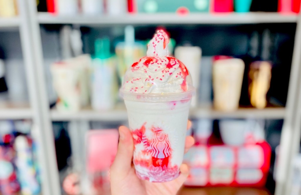 hand holding santa frappuccino in front of store shelves 
