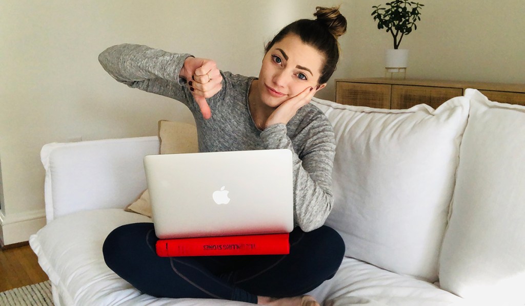woman sitting on couch using a book as a lap desk for MacBook