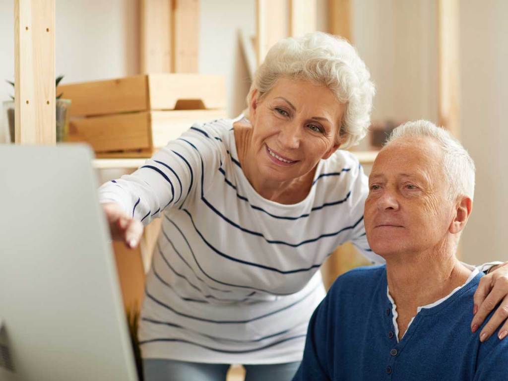 An elderly couple using a laptop to sign up for the Affordable Connectivity Program