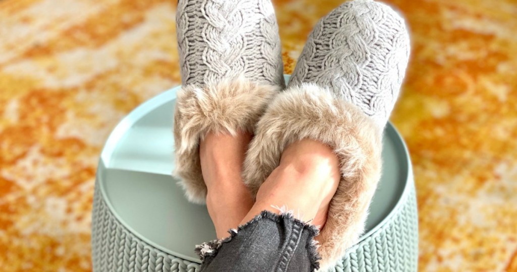 woman wearing grey knit slippers with her feet up on an ottoman