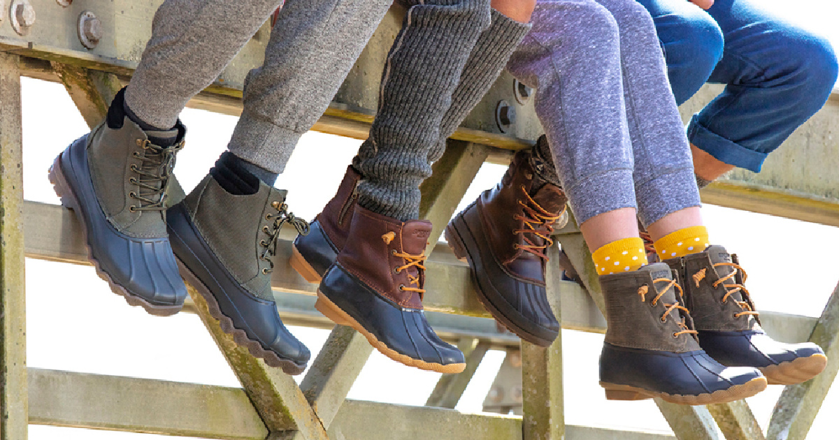kids sitting on a wooden railing with legs dangling showing their duck boots