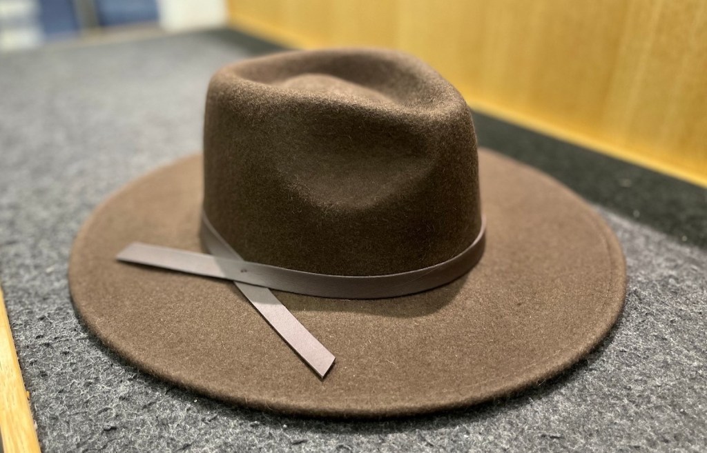 wide brim hat with leather strap sitting on carpet surface in store