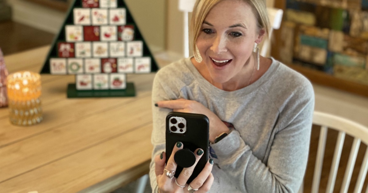 woman looking at iPhone with Christmas advent calendar in the background