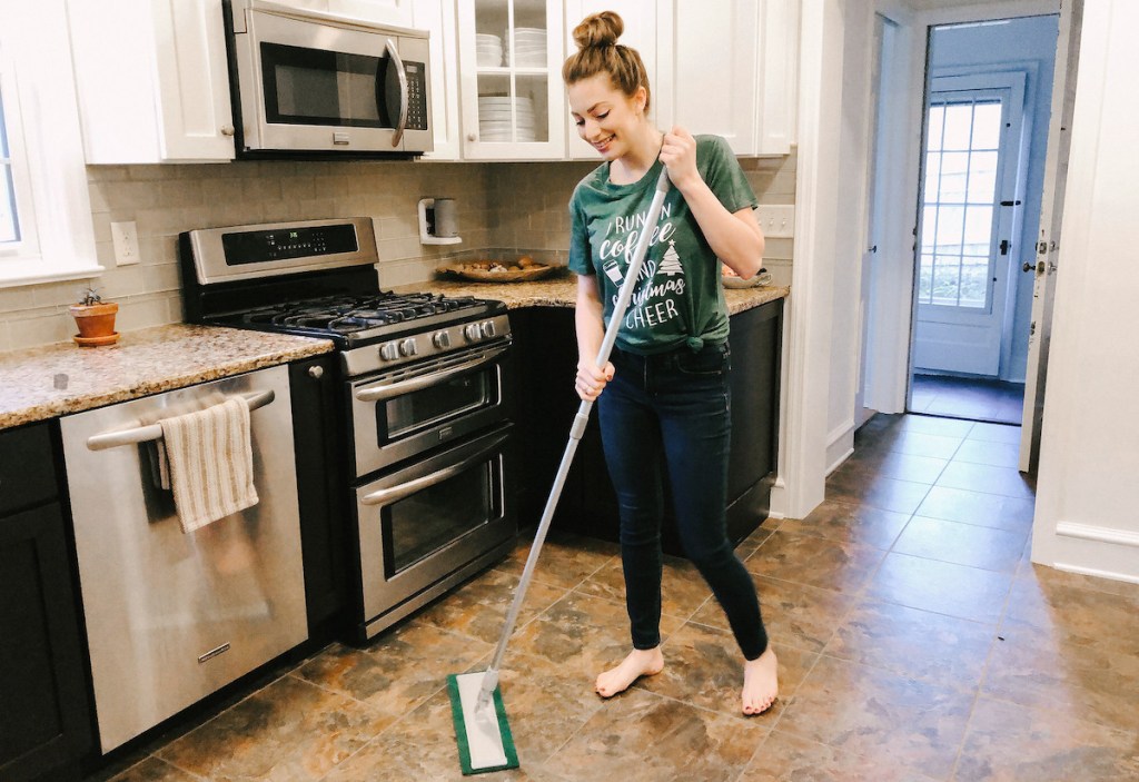 woman holding cleaning mop standing in kitchen