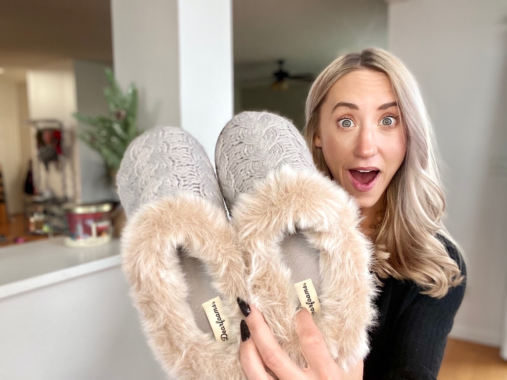 woman holding dearfoams fuzzy slippers