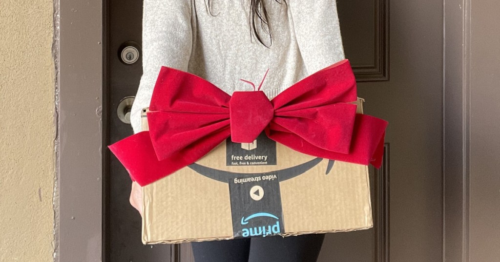 woman holding Amazon box with red bow