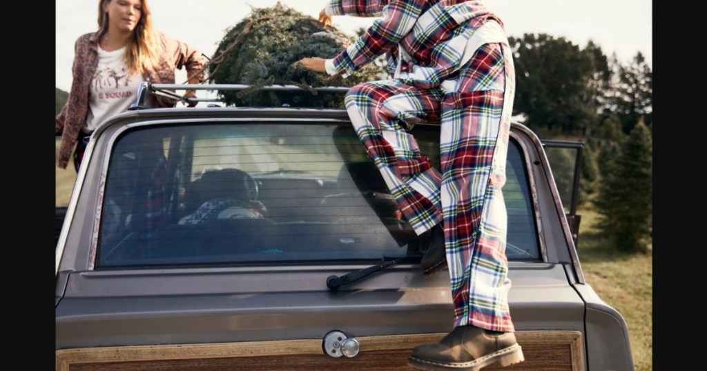 woman in flannel pajamas climbing on a car